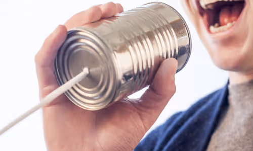 A man is speaking through a tin can phone